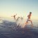 Group of friends running in to sea at sunset